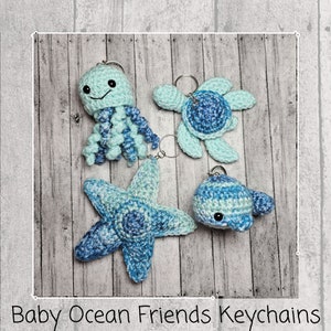 Può includere: Quattro portachiavi all'uncinetto a forma di animali marini: un polpo blu e verde, una tartaruga blu e verde, una stella marina blu e verde e una balena blu e verde.  Portachiavi Baby Ocean Friends.