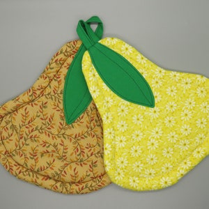 May include: Two pear-shaped pot holders, one with a yellow background and white daisy print, and the other with a brown background and a leafy pattern. Both have green fabric leaves.