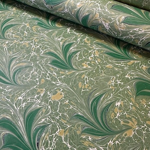 May include: A roll of decorative paper with a marbled pattern. The design features swirling green, white, and gold colors. The paper has a flowing, organic design, with a mix of light and dark shades of green.