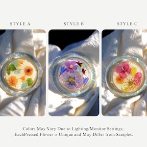 May include: Three round, clear resin pieces with pressed flowers inside. Style A features orange and yellow flowers, Style B has purple and blue flowers, and Style C displays pink and yellow flowers. The text reads: "STYLE A", "STYLE B", "STYLE C".