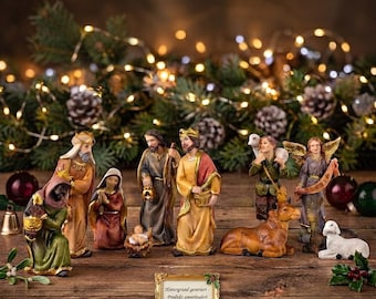 Könnte beinhalten: Ein Krippenset mit handbemalten Figuren der Heiligen Familie, der Heiligen Drei Könige, einem Engel, einem Hirten und Tieren. Ein kleines goldenes Schild in der Mitte zeigt den Text: Hintergrund generiert - Produkt unverändert.