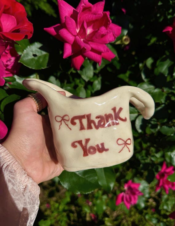 A hand-sculpted ceramic shopping bag planter complete with bows — whimsical trompe-l'oeil pottery that makes you do a double-take.