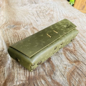 Puede incluir: Una funda de cuero verde con cierre de solapa y dise&ntilde;o cosido. La funda tiene el nombre de la marca "kobo" grabado en relieve en la solapa. La funda tiene tachuelas met&aacute;licas alrededor de los bordes.