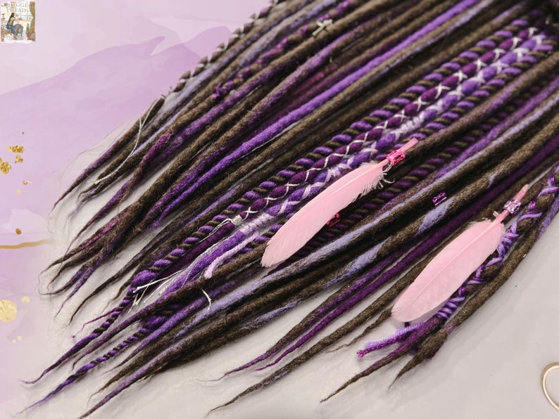May include: A set of brown and purple synthetic dreadlocks with pink feathers. The dreadlocks are made of wool and have a variety of textures.