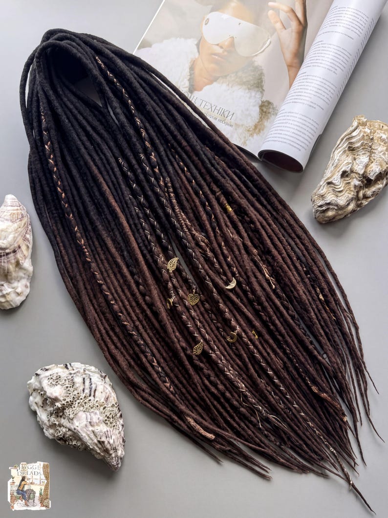 a collection of various objects, including a long, dark brown braided hairstyle, a magazine, and some shells.