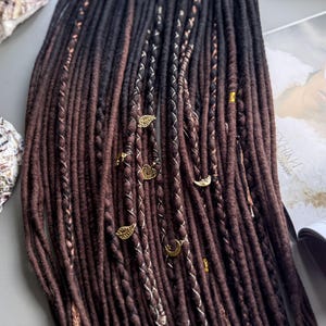 a collection of brown braided hair accessories, including beads and charms, arranged on a surface alongside a magazine or book.