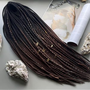 a collection of hair accessories, including a long braided hairstyle, seashells, and a magazine with a picture of a woman.