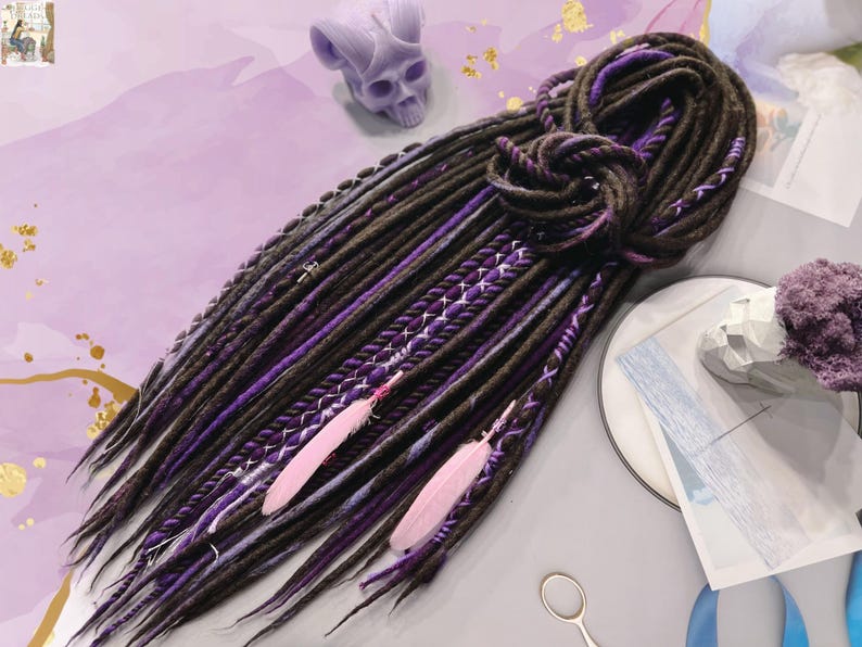 May include: A set of brown and purple synthetic dreadlocks with pink feathers. The dreadlocks are tied together at the top.