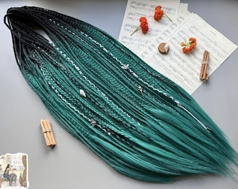 Dreadlocks sintéticos em tons de preto a verde esmeralda, tranças espinha de peixe e extensões ombré.