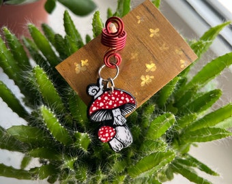 May include: Red and white mushroom charm with a snail on top, hanging from a red wire hair coil.