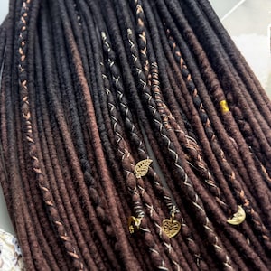 a close-up view of a collection of dark brown braided hair accessories, including beads and charms, arranged in a row.