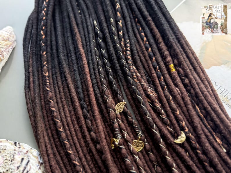 a close-up view of a collection of dark brown braided hair accessories, including beads and charms, arranged in a row.