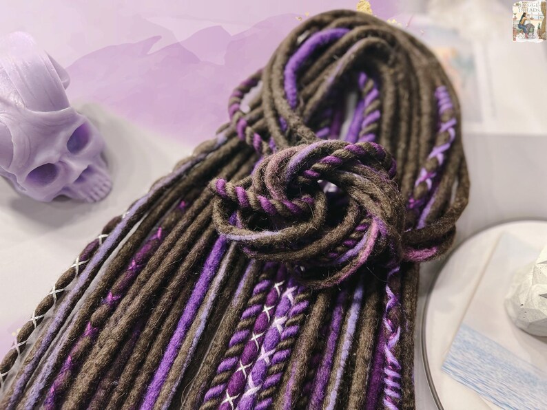 May include: A bundle of brown and purple synthetic dreadlocks. The dreadlocks are made of a soft, textured yarn and are ready to be added to your hair.