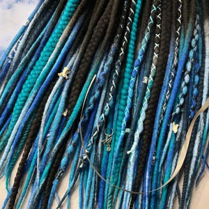 May include: A set of blue and black synthetic dreadlocks with silver charms. The dreadlocks are made of wool and are approximately 24 inches long.