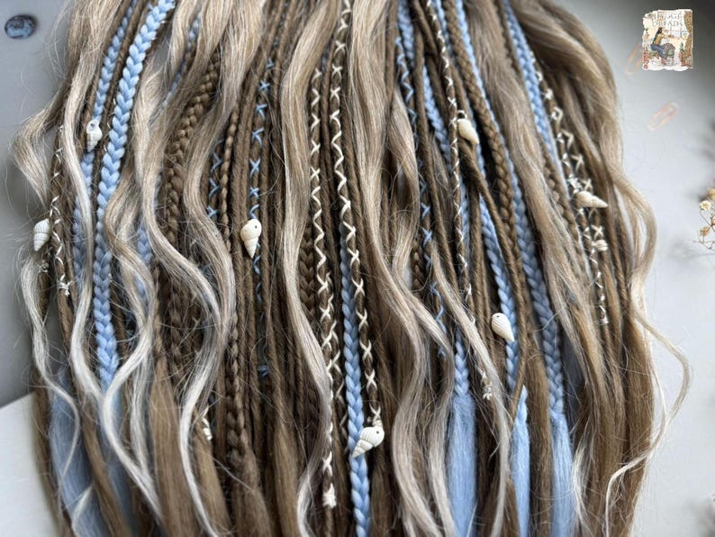 a close-up view of a person's long, braided hairstyle with various colored braids and decorative elements such as shells.