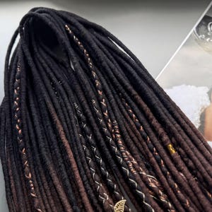 a collection of long, dark brown braided hair strands arranged on a surface, with a magazine featuring a woman's face in the background.