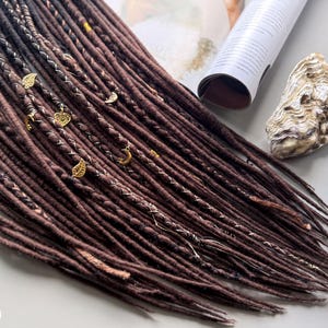 a collection of brown braided hair accessories, including beads and a shell, arranged on a surface.