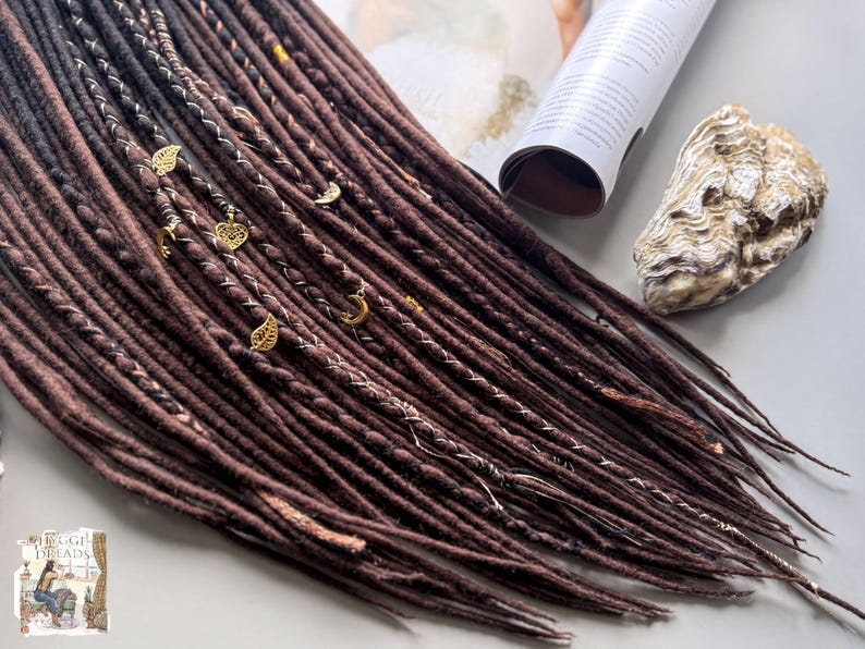 a collection of brown braided hair accessories, including beads and a shell, arranged on a surface.
