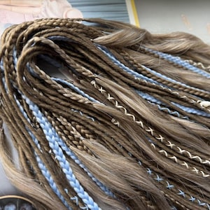 A close-up view of a bundle of braided hair in various shades of brown and blue, arranged in a complex and intricate manner.
