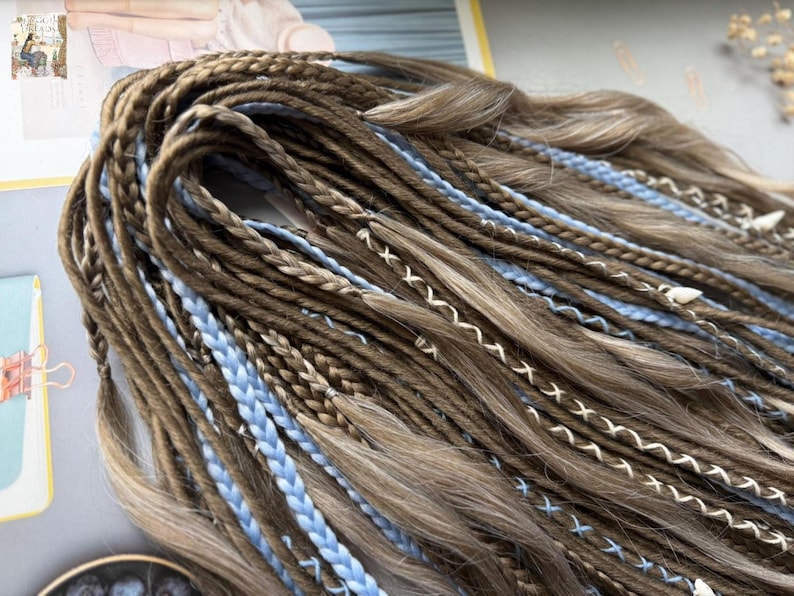 A close-up view of a bundle of braided hair in various shades of brown and blue, arranged in a complex and intricate manner.