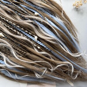 a close-up view of a person's long, braided hairstyle with various colored braids and decorative elements such as beads and flowers.