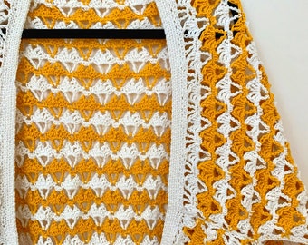 May include: A crocheted cardigan with a yellow and white pattern. The cardigan has a loose fit and a V-neck.