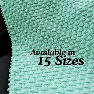 May include: A mint green crocheted blanket with a textured, raised pattern. The blanket is folded, revealing the intricate stitch work. Text on the blanket reads "Available in 15 Sizes".