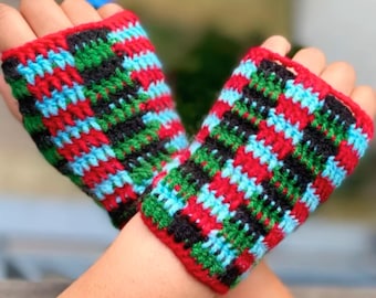 May include: A pair of fingerless crochet gloves featuring a repeating checkered pattern in red, black, green, and light blue yarn. The text "Beginner · 1 Hour Project · PDF Download" is printed in a white box at the bottom of the image.