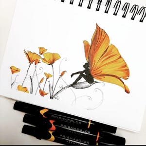 Op de afbeelding: Een schets van een fee met oranje vlindervleugels die op een blad zit, met oranje bloemen en stelen. De tekening staat op een wit spiraalgebonden schetsboek. Vier Prismacolor Premier markers staan onderaan.