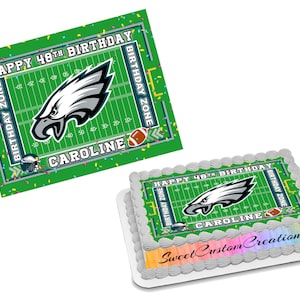 May include: Green and white edible cake topper with a football field design. The topper features a Philadelphia Eagles logo with the words "Happy 48th Birthday" and "Birthday Zone" on either side. The name "Caroline" is printed below the logo.