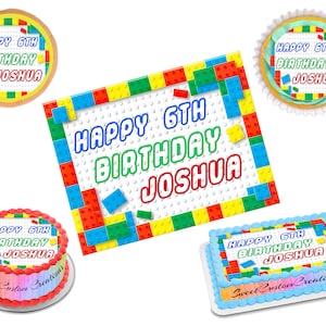 May include: A set of four edible cake toppers featuring a Lego-themed design with the text "Happy 6th Birthday Joshua". The toppers are in various sizes and shapes, including a round cake topper, a square cake topper, and two rectangular cake toppers.