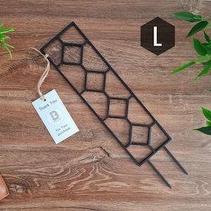 Op de afbeelding: Zwarte metalen plantenspalier met een geometrisch ontwerp. De spalier is maat L en heeft twee pinnen om in de grond te steken.