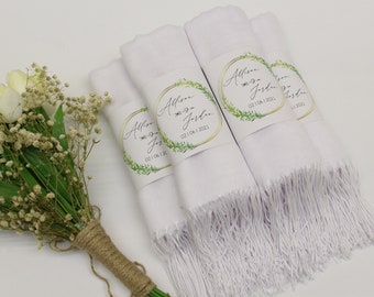Könnte beinhalten: Weiße Hochzeitsschals mit personalisierten Etiketten mit den Namen "Allison & Jordan" und dem Hochzeitsdatum "02.06.2022". Die Etiketten haben einen goldenen Kreis mit einem grünen Blätterkranz darum.