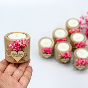 May include: Set of small wooden candle holders with a heart-shaped tag that says "Dean & Julie 08.08.2024" and pink dried flowers.
