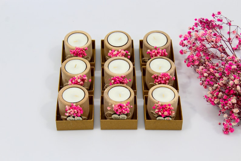 May include: Ten small wooden candle holders with pink flowers and a heart-shaped tag that says "Dawn & Julie" on each. The candle holders are arranged in two rows of five.