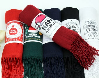 May include: Five different colored scarves with fringe. Each scarf has a different Christmas themed label with text that reads "Merry Christmas", "Happy Holidays", "We Wish You a Merry Christmas", and "Merry Xmas".