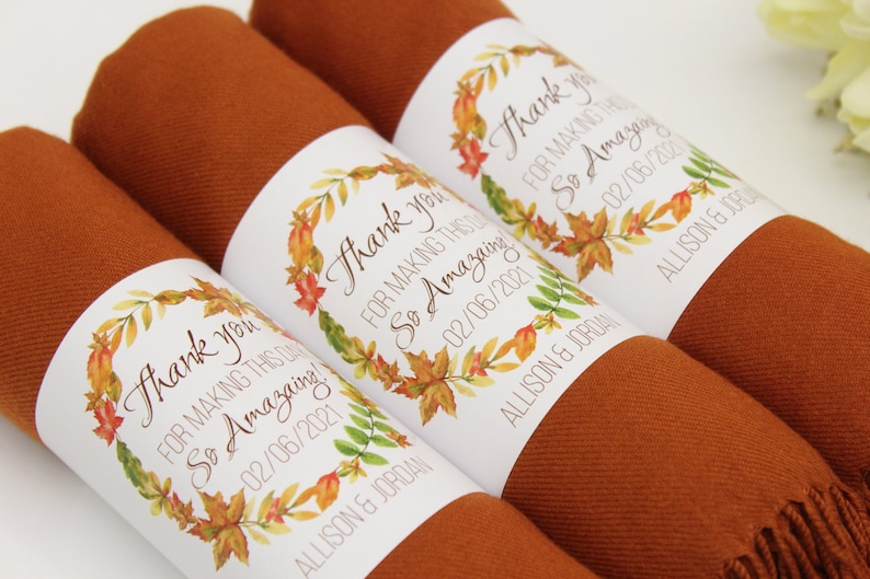 May include: Three brown scarves with white labels that say "Thank you for making this day so amazing" with a watercolor wreath of fall leaves and the date "02/06/2021" and the names "Allison & Jordan".