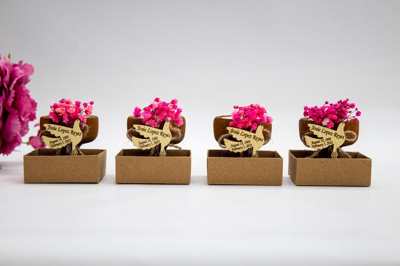 May include: Four small brown boxes with pink dried flowers and a wooden dove with the text "Josie Lopez Reyes August 11, 2020 February 1, 2023" on each.