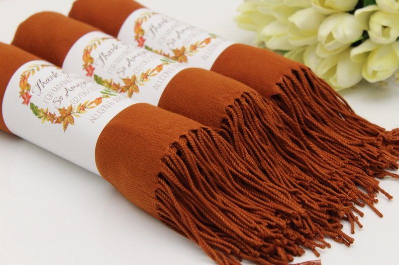 May include: Three rust-colored scarves with white labels that say "Thank you for making our day so amazing!" with a fall-themed wreath design. The labels also include the date "02/18/2017" and the names "Allison & Eric".