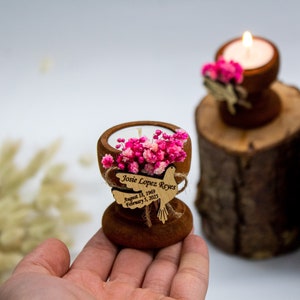 May include: A small wooden candle holder with a white candle and pink flowers. A wooden dove with the text "Josie Lopez Reyes August 1st, 1969 February 3, 2023" is attached to the holder.