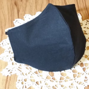 May include: A black fabric face mask with a simple design. The mask is made of a soft, breathable material and is designed to cover the nose and mouth.