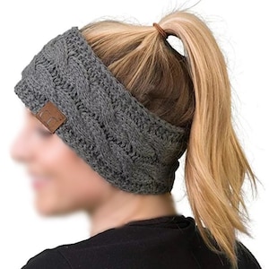 Könnte beinhalten: Grauer Strick-Stirnband mit einem braunen Leder-Patch. Das Stirnband wird von einer Person mit blonden Haaren getragen, die zu einem Pferdeschwanz gebunden sind.