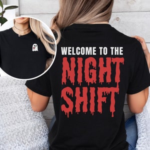 Peut inclure: T-shirt noir avec un fant&ocirc;me blanc sur le devant et un texte rouge qui coule sur le dos qui dit "Bienvenue &agrave; l'&eacute;quipe de nuit".