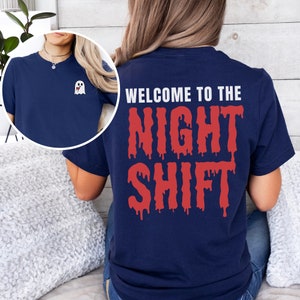 Peut inclure: Un t-shirt bleu marine avec un motif de fant&ocirc;me blanc sur la poche avant et le texte "WELCOME TO THE NIGHT SHIFT" en lettres rouges qui coulent au dos.