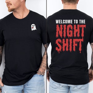 Peut inclure: T-shirt noir avec un motif de fant&ocirc;me blanc sur le devant et "WELCOME TO THE NIGHT SHIFT" en lettres rouges qui coulent sur le dos.