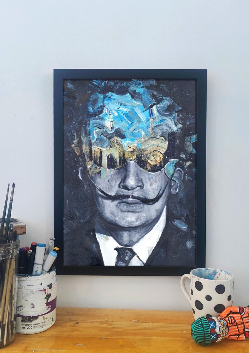 May include: A framed painting of a man with a moustache and sunglasses. The background is a blue and white abstract design.
