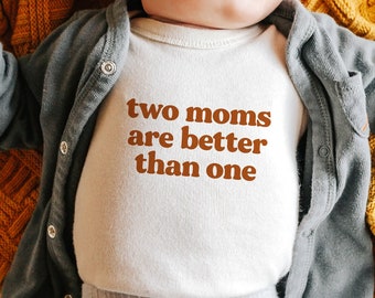 May include: A white baby onesie with the text "two moms are better than one" printed in brown.