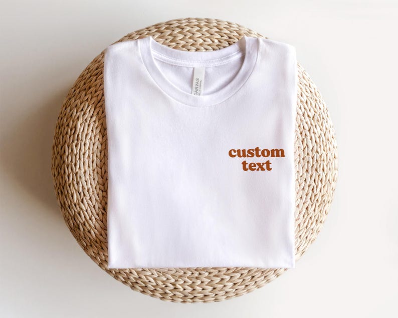 May include: White t-shirt with the text "custom text" in brown lettering on the front.
