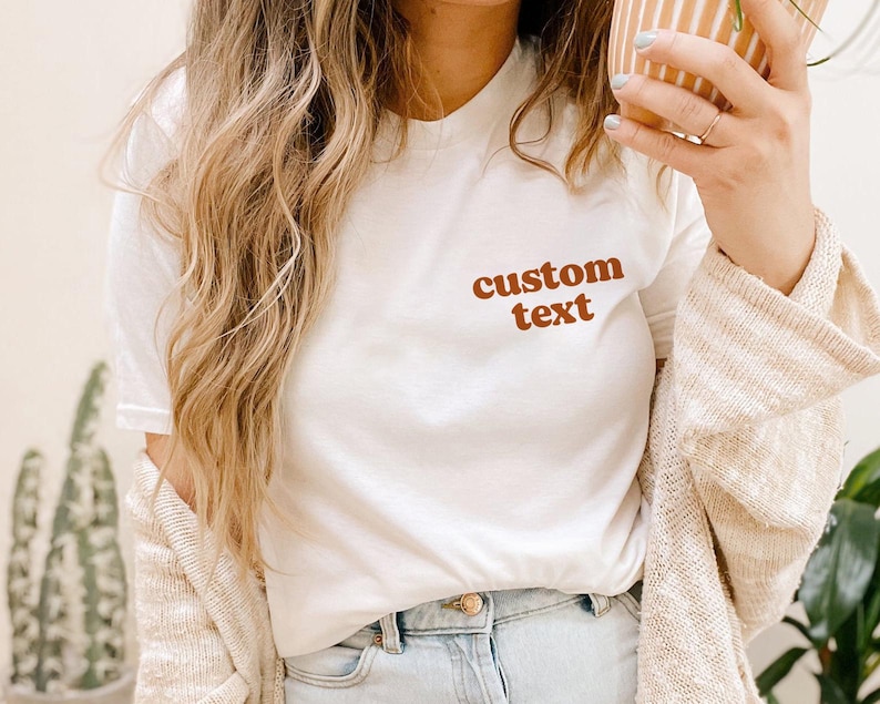 May include: White t-shirt with the text "custom text" in brown lettering.