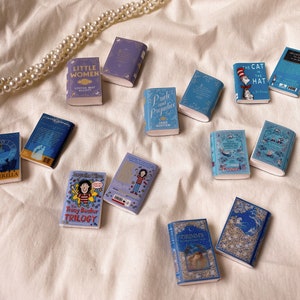 Seven pairs of books laid out flat to show the covers. These are all blue or purple in colour. Cinderella. Little women. Pride and prejudice. The cat in the hat. The tracy beaker trilogy. Alice's adventures in wonderland. Grimm's fairytales.